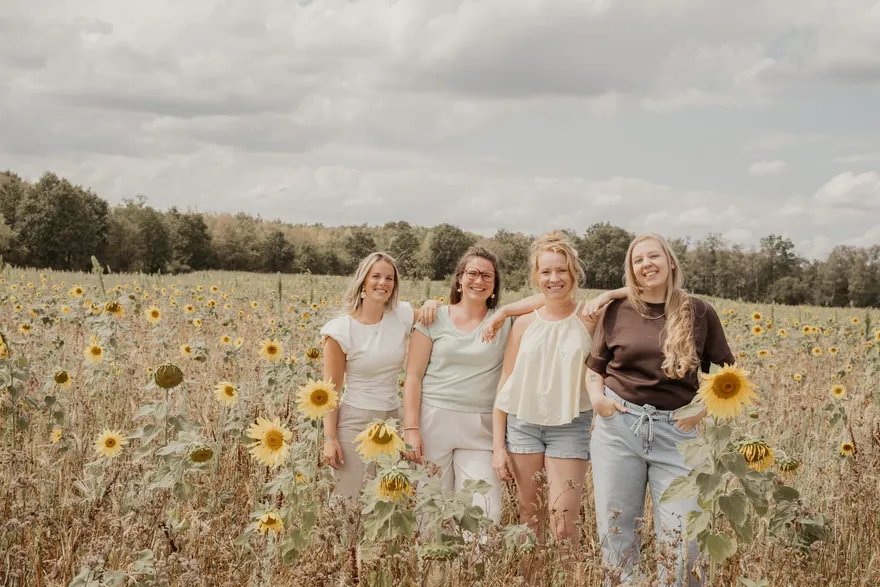 De vier vroedvrouwen van Juno samen in een zonnebloemenveld